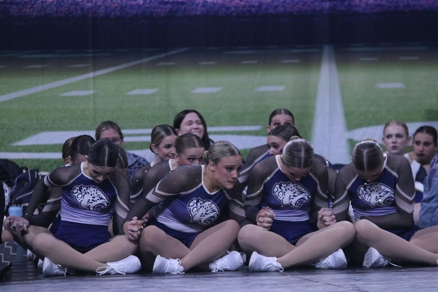 The team holds hands nervously as they await the judge’s announcement of their state championship win. 
