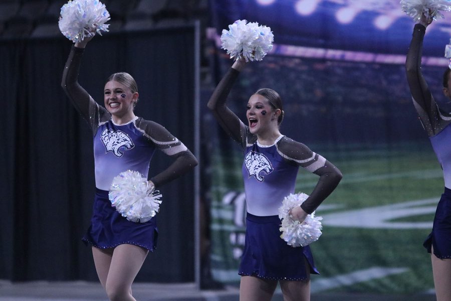 Arms raised with poms in hand, junior Halle Wampler and freshman Savannah Seymour perform their band dance routine. 
