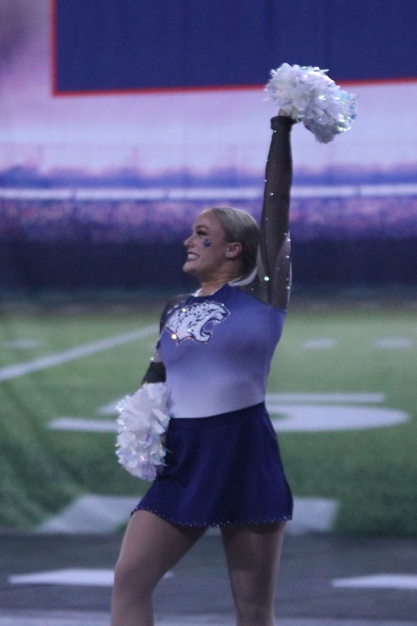 With her knee popped and her hand in the air, junior Trinity Baker performs with a smile on her face. 
