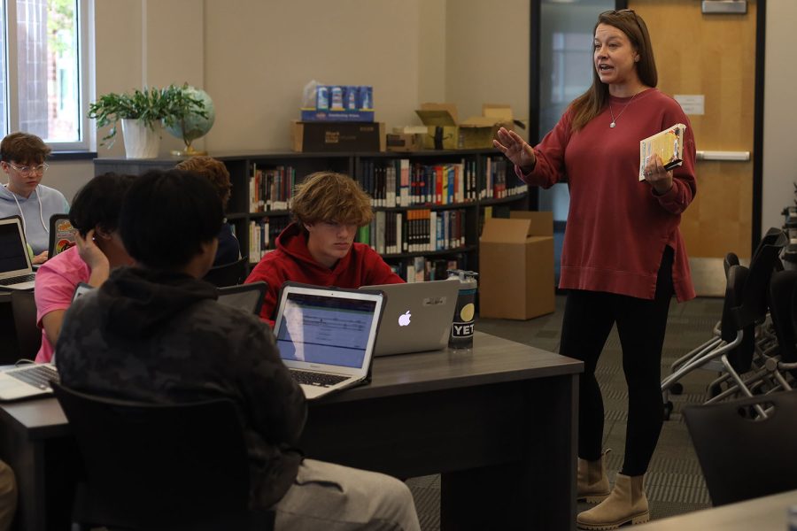 Standing in front of a group, librarian Ashley Agre talks to the students about a book.