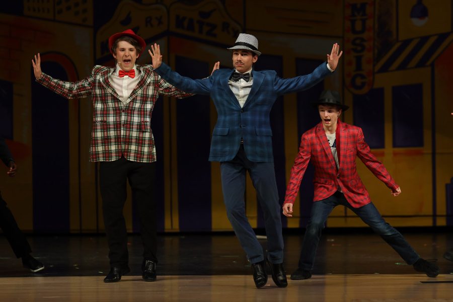 With their arms in the air, sophomore Ayden Brown, senior Jameson Beran and freshman Drew Cormany dance to “Fugue for Tinhorns.”