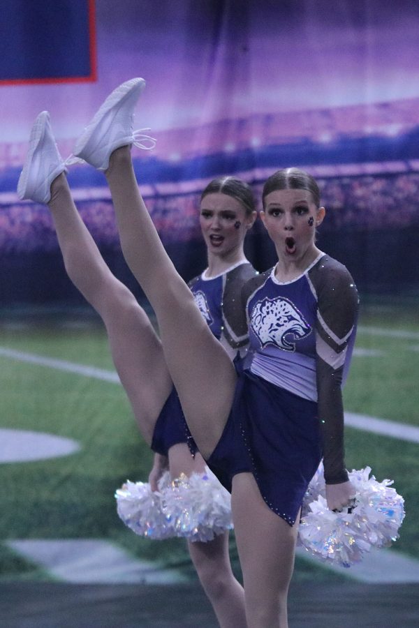 Kicking their legs up, freshmen Ella Jones and Brooke Seymour show off their flexibility. 
