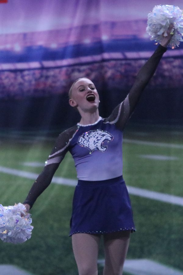 Yelling out with her arms up, freshman Preslie Wampler performs for the crowd. 
