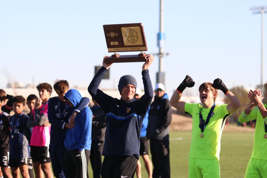 With the trophy in the air, head coach Jason Pendleton shows off the state championship title.