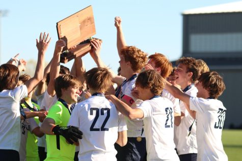 Holding their trophy overhead, the Mill Valley boys soccer team celebrates winning the state championship title.
