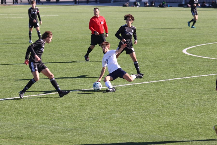 With opposing players approaching, sophomore Brady Robins slides to kick the ball down the field to a teammate.