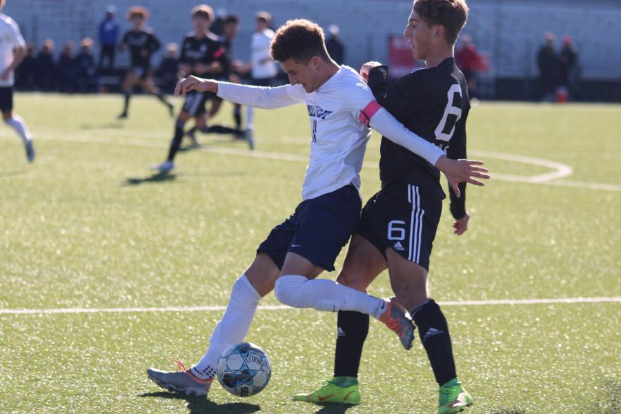 With the ball at his feet, senior Dylan Ashford kicks the ball away from the opposing player.