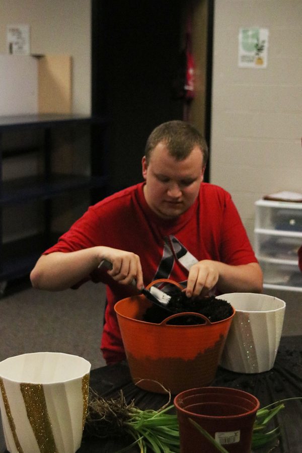 With a shovel in his hand and potting on his mind, senior Gus Gosch shovels soil into an already decorated plastic pot Wednesday, Oct. 26. 