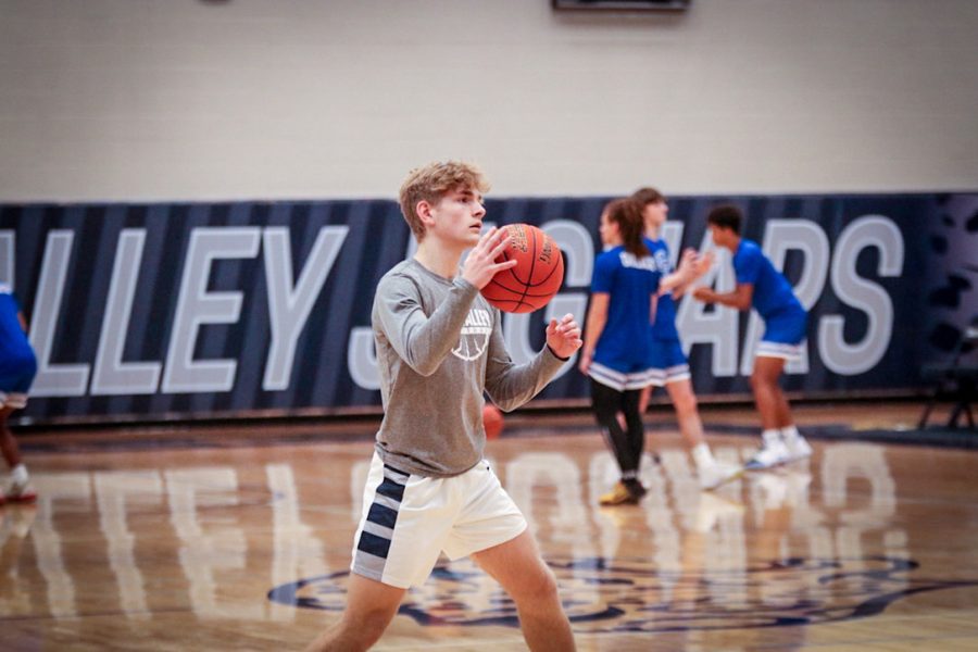 Warming up before the game, junior Bryant Wiltse dribbles the ball across the court Friday, Dec. 9.