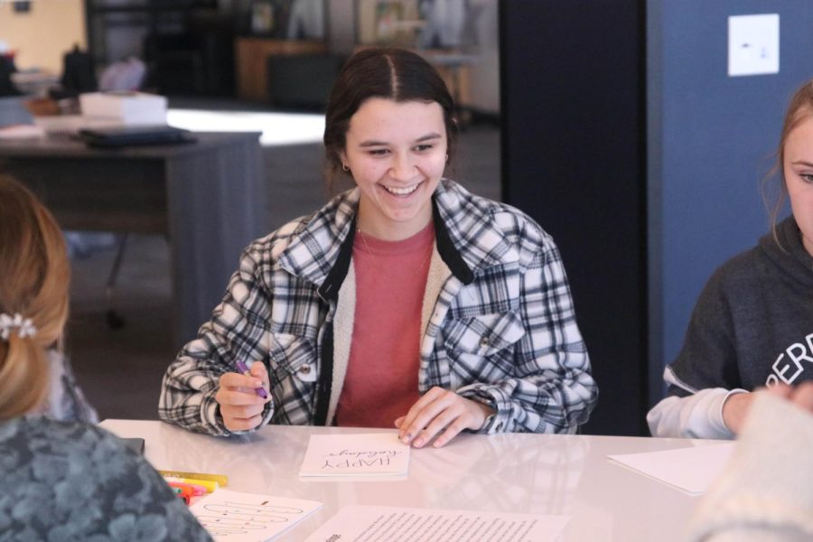 Looking up from her card, senior Makenna Arnold smiles at her friends card.