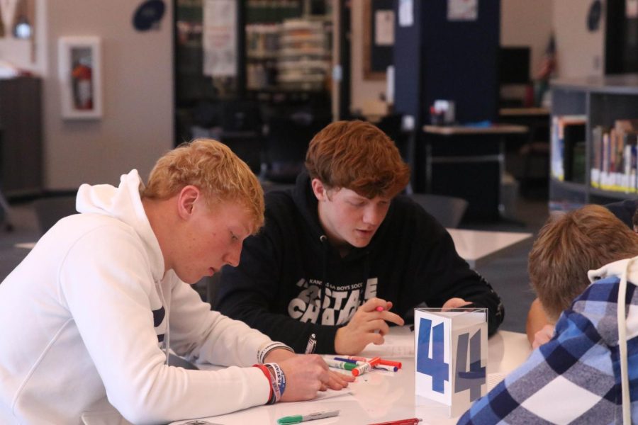 Looking down at their cards, seniors Mikey Bergeron and Owen Peachee write letters.