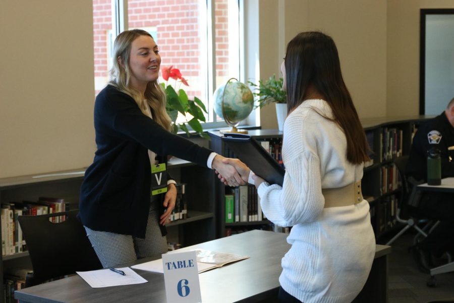 Reaching across the table, freshmen Nadia Kindt shakes hands with her mock-interviewer.