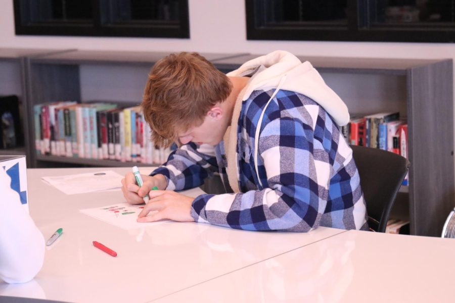 Green marker in hand, senior Tate Nekola creates a card for Love For Our Elders.