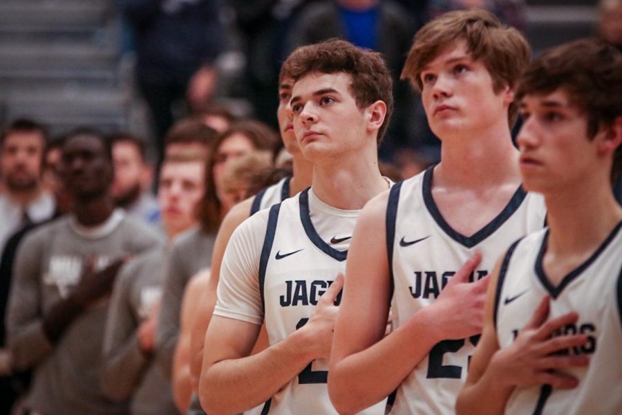 Senior Ryan Cummings, sophomore Carter Kaifes and senior Brooks Jahnke stand in line with their teammates for the regular playing of the Star Spangled Banner.