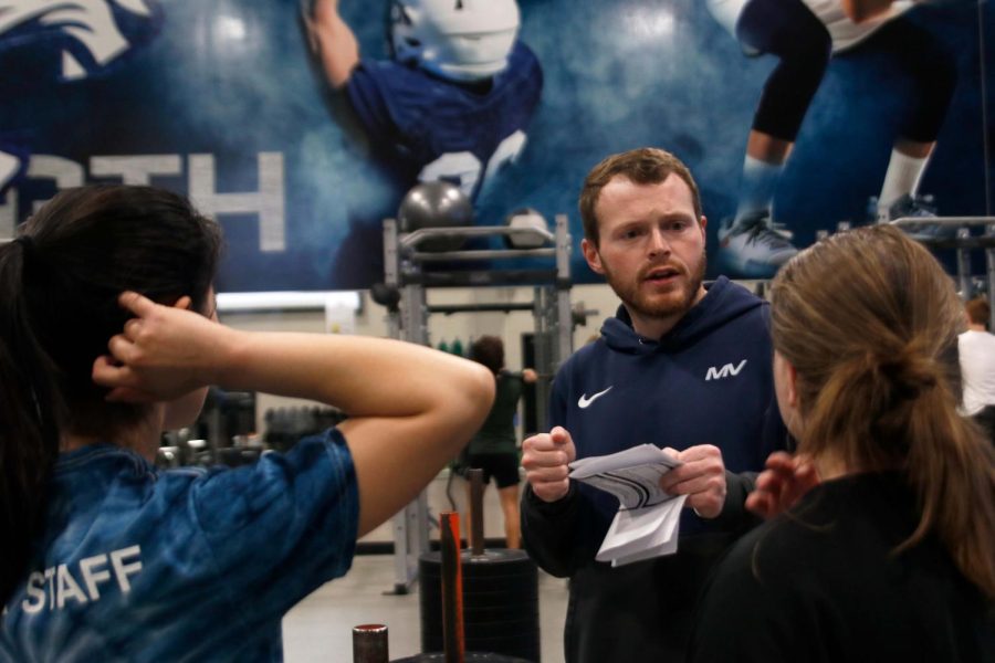 Holding practice plans, girls powerlifting coach Josh Barnes talks to students on Thursday, Dec. 8