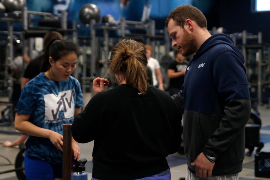 Head down, Coach Barnes reviews a powerlifting spreadsheet with students.