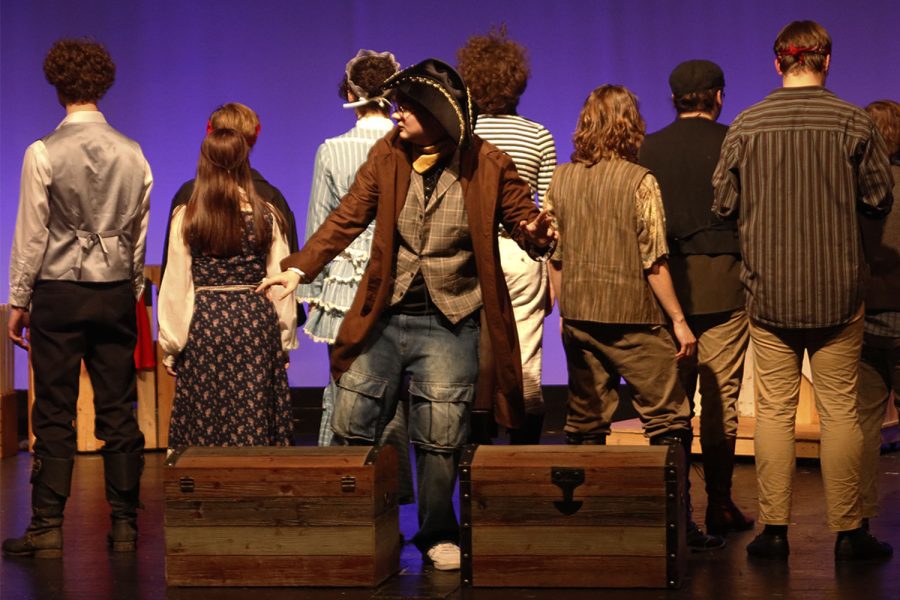 Standing behind two unopened chests, junior Nathan Garner is surrounded by other cast members who have their backs turned as a way to add a touch of suspense and mischief Tuesday, Dec. 6. 