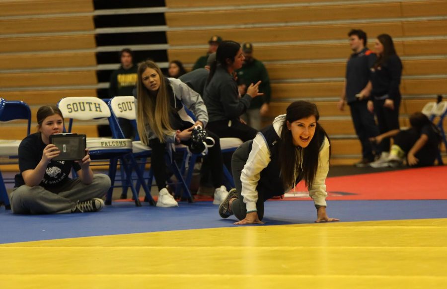 Coaching a wrestler, head coach Michelle McCray puts her hands down on the mat.