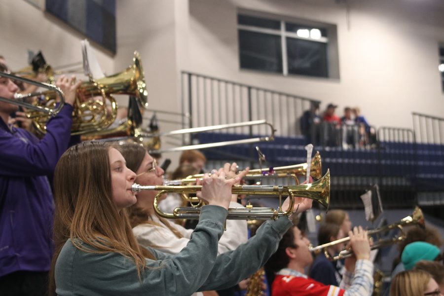 Holding up her music lyre, senior Audrey Facer plays on her trumpet next to sophomore Joah Clark. 