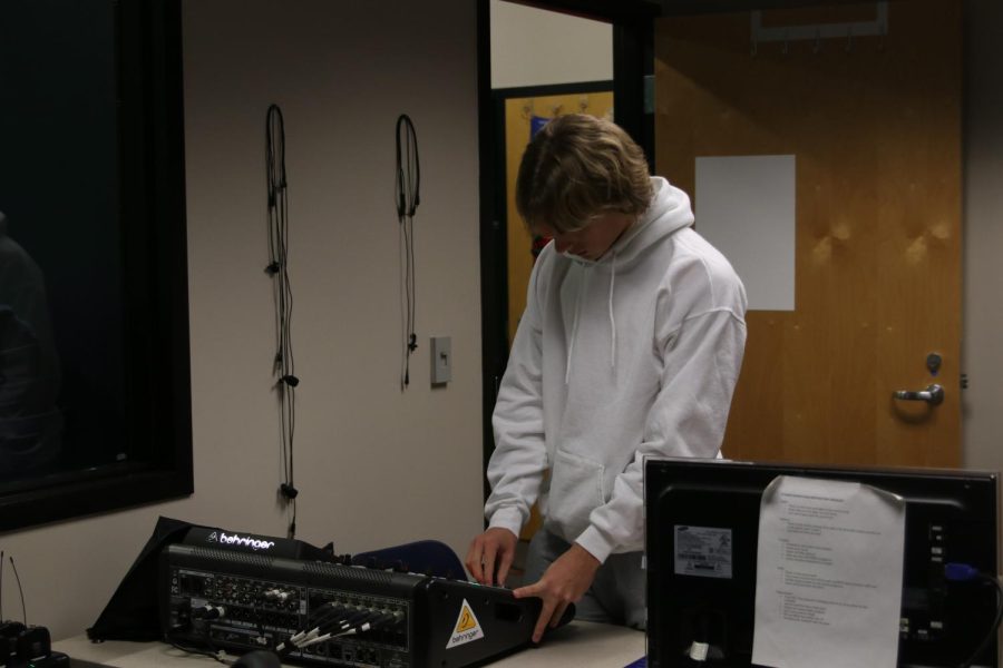 Turning the knobs, Senior Alex shank uses the soundboard to test sound in the studio.