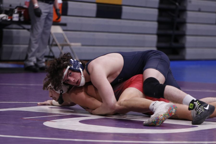Looking at the clock and score, junior Maddox Casella holds his opponent down.