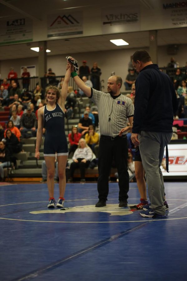 Raising her hand, freshman Finley Rose smiles after winning her match.