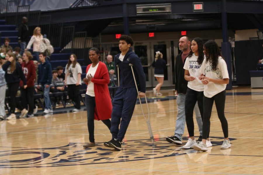 Alongside his family, senior Jameson Fisher makes his way across the court.