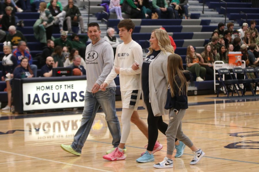 In between his parents, basketball senior Brooks Jahnke is recognized for senior night.