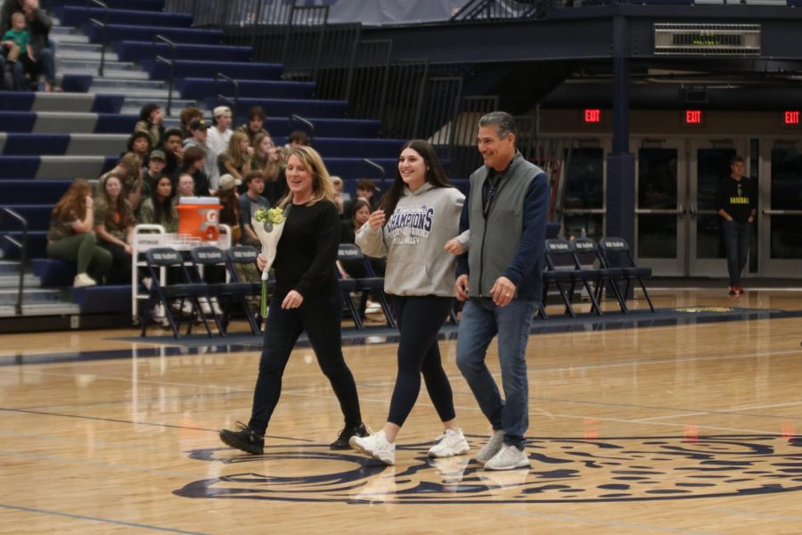 With a smile on her face, senior Torri Olivarrez walks between her parents.