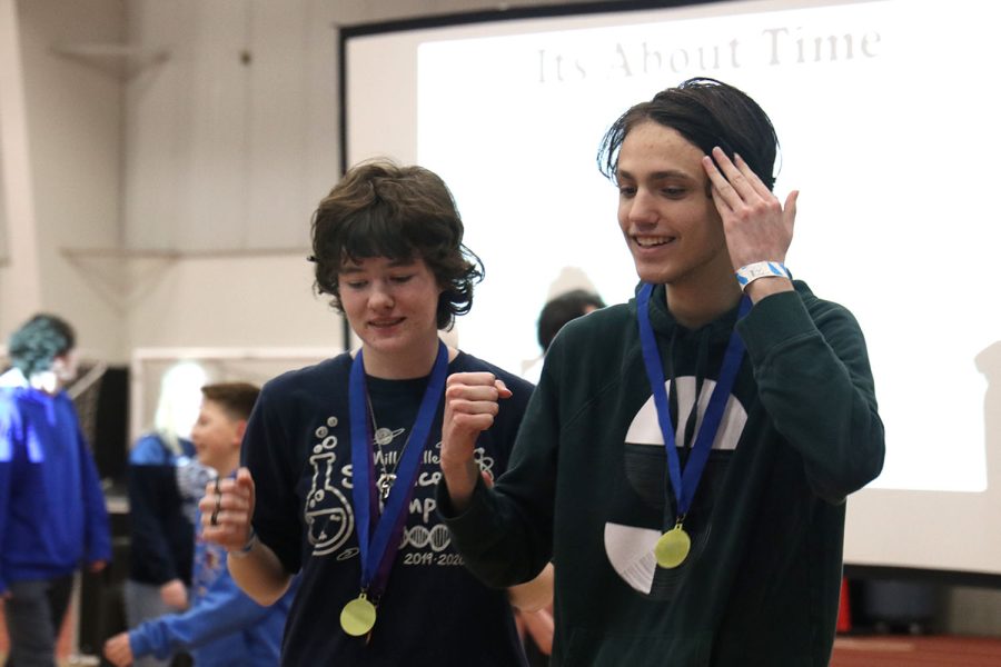 Fists raised in triumph, seniors Sydney Downey and Jackson Wilhoit approach their team with their first place medals in It’s About Time.