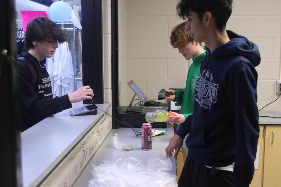 During seminar, senior Sonny Pentola counts change for a student buying snacks alongside senior Diego Martin Del Campo. 