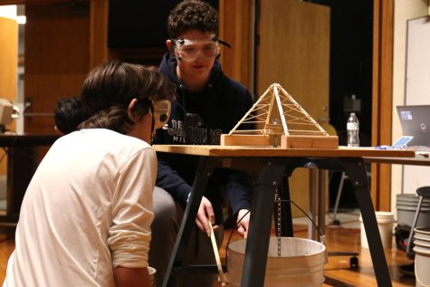 Leaning on the tips of their toes in anticipation, freshmen Ethan Austin and Miles Brown listen for cracking as weight is added to their bridge Saturday, Feb. 25.