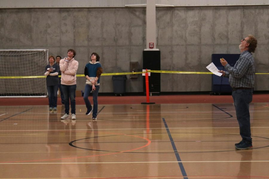 Senior Sydney Downey and sophomore Carter Tollman watch their plane soar in anticipation as the competition judge records the time it spends in the air.