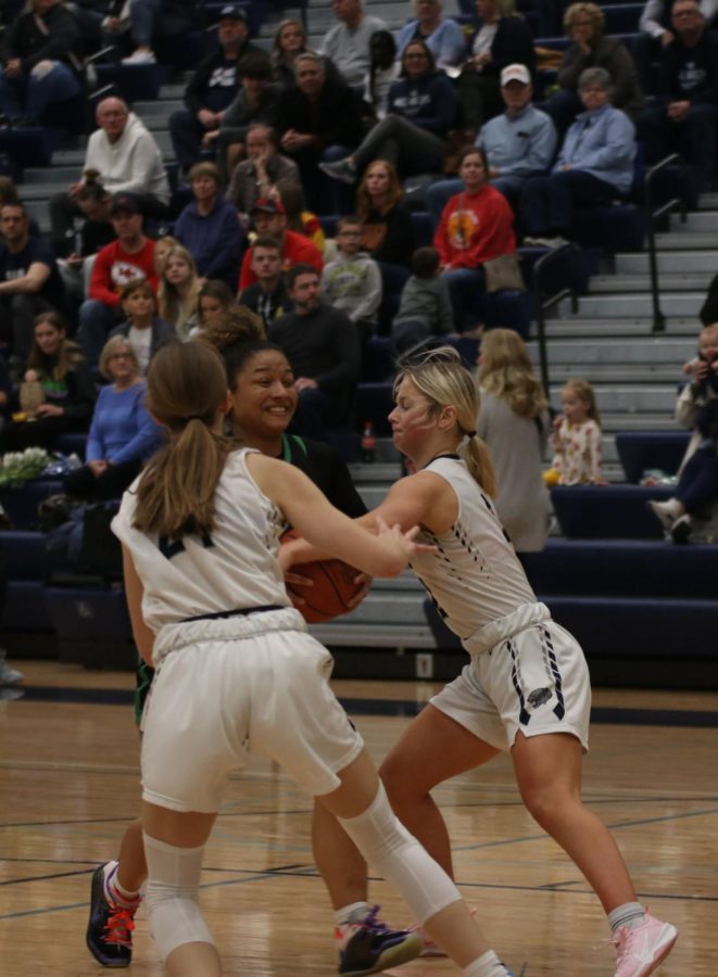 Blocking a Shawnee Mission South player, sophomore Averie Landon and junior Keira Franken try to get the ball back.