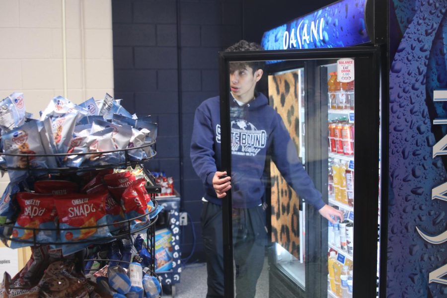 After asking a student what they want, vice president of marketing senior Diego Martin reaches for a Celsius energy drink.