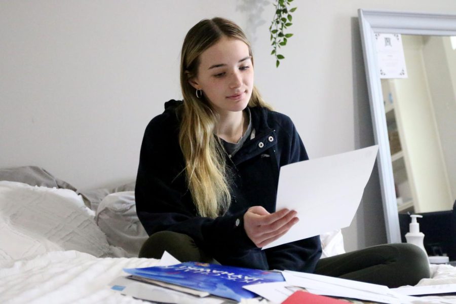 Sitting+on+her+bed%2C+senior+Libby+Strathman+looks+through+her+collection+of+college+acceptance+letters.+Strathman%2C+who+applied+to+eight+different+universities%2C+carefully+crafted+her+college+resume+by+getting+involved+in+various+extracurriculars.+