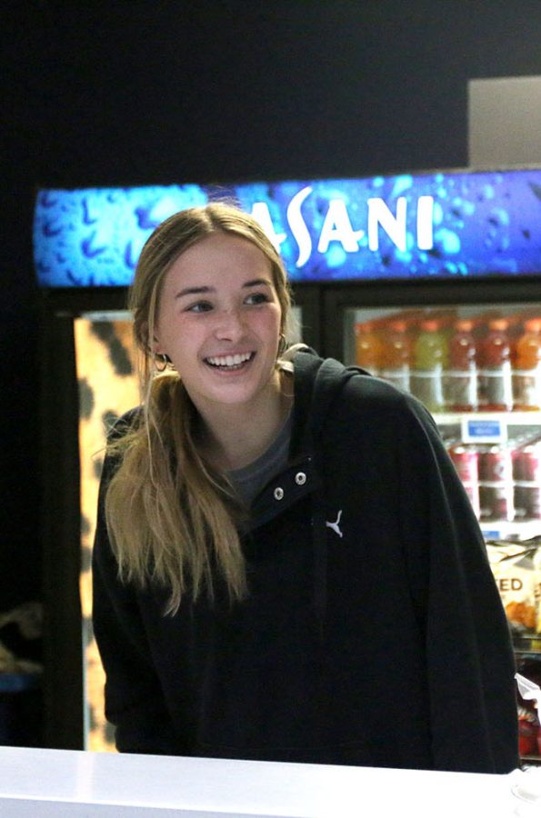 Looking over the counter, senior Libby Strathman beams at the first student-customers in line at the Catty Shack Tuesday, Jan. 24.