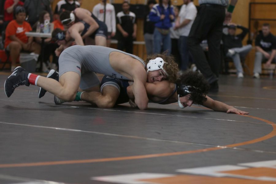 Arms wrapped around his opponent, junior Brady Mason grabs hold of him.