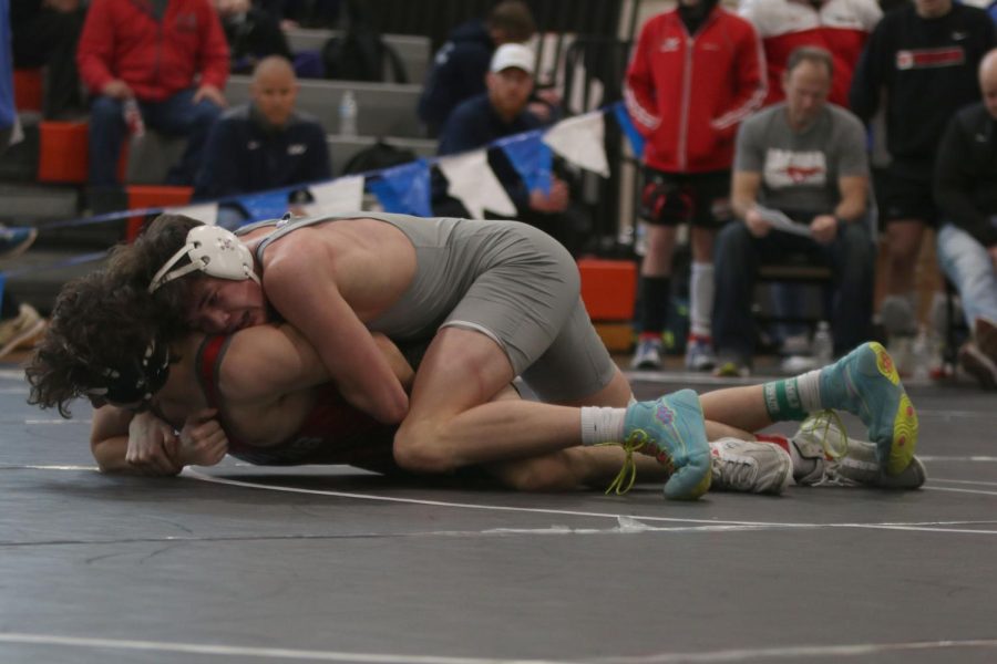 Holding his opponent under him, senior Dylan Massey focuses on pinning him.