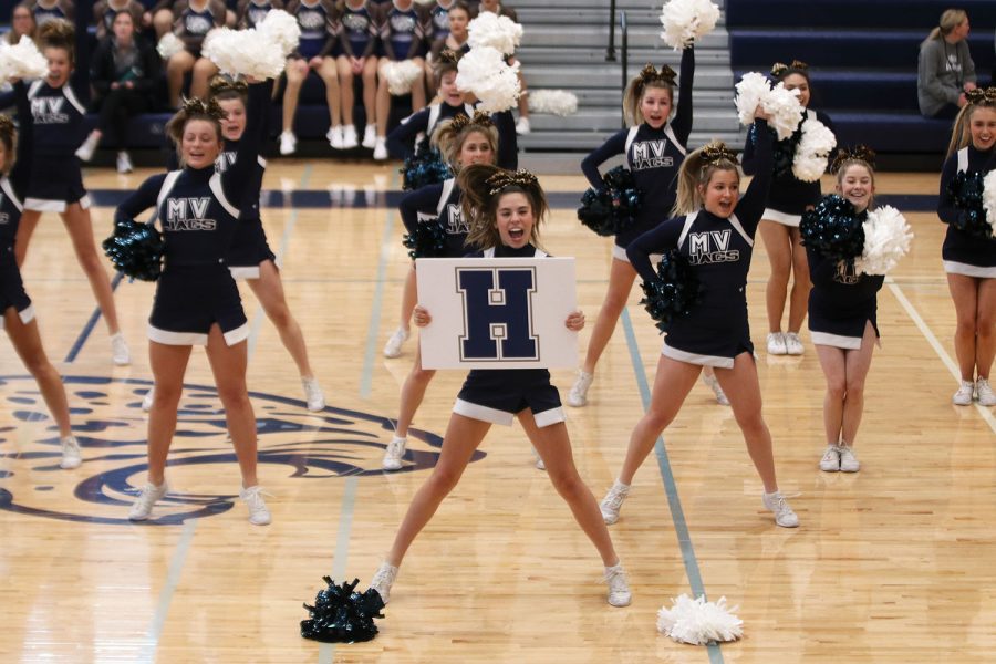 Posing, senior Sidney Claeys holds the board during the cheer performance. 