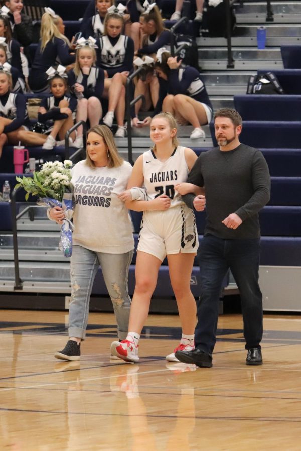 As she walks towards the others, senior Ryleigh Kennedy holds onto her parents arms. 