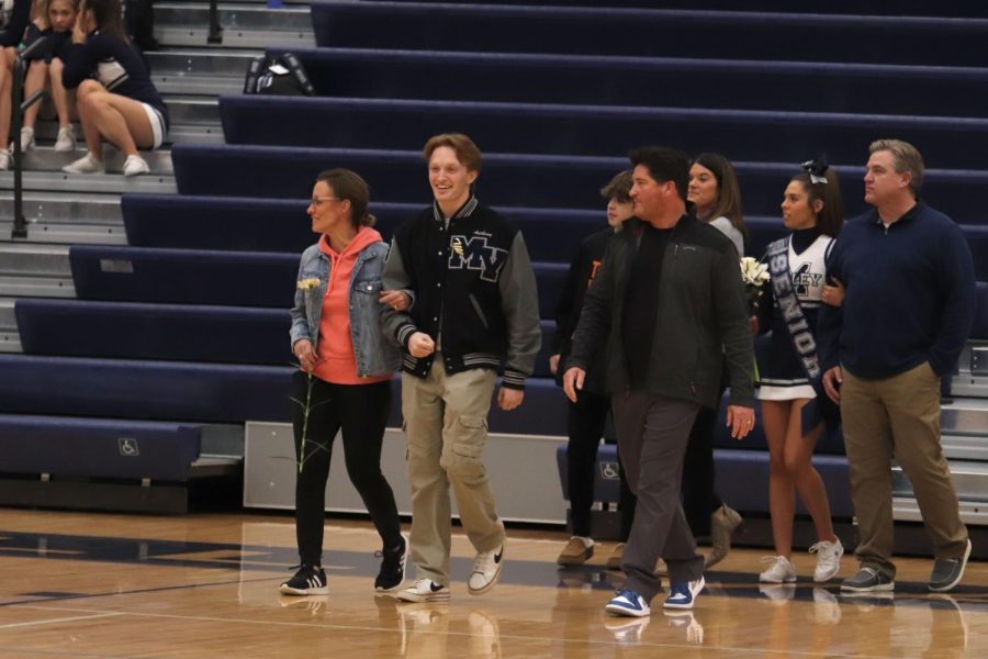 With his parents by his side, senior Anthony Molinaro walks during the senior night ceremony. 