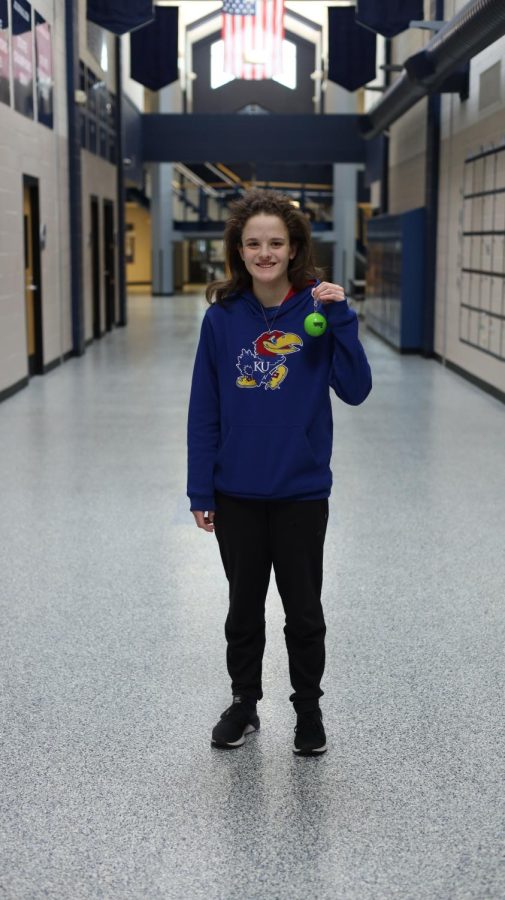 Senior Mallory Botts holds up a poncho inside of a case Thursday, March 9. Botts said she is packing her poncho because it’s supposed to rain while we are [in Florida].”