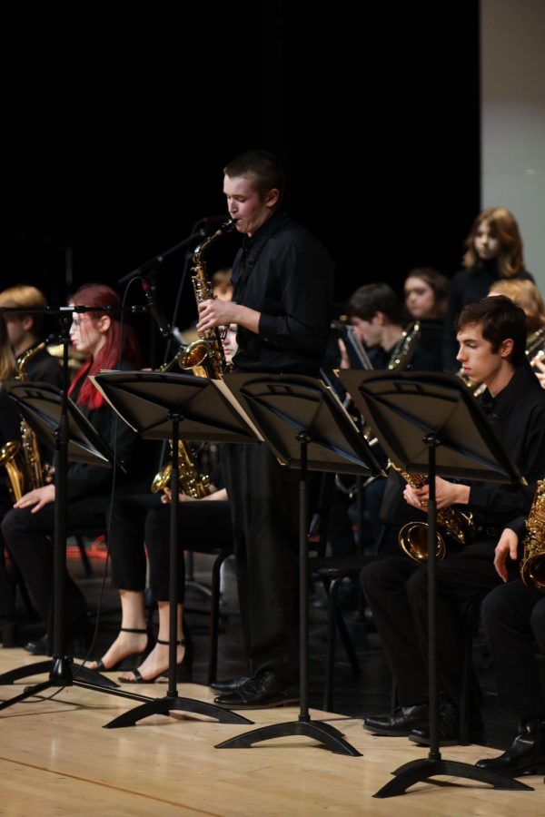 Standing up for his solo, senior Brody Shulda plays the saxophone.