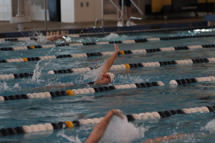 Reaching her arm back, junior Ella Hansen swims backstroke during the 200 meter individual medley race, placing first.