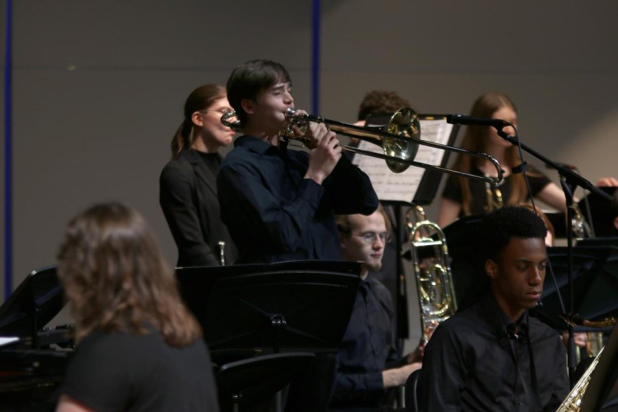 In the middle of a solo, senior Colin Scherzer stands to play his trombone.