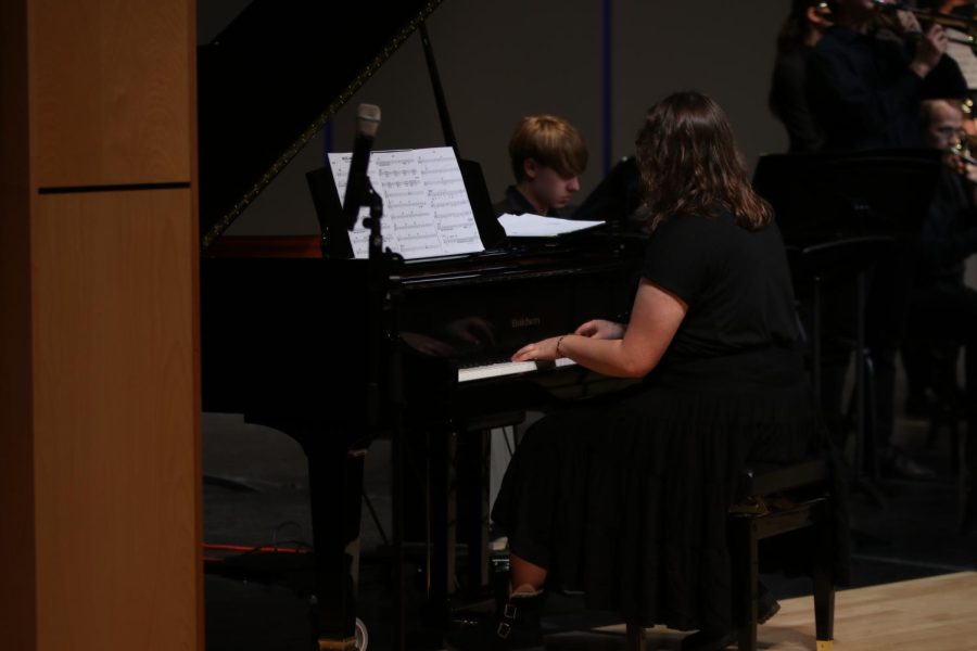 In the corner of the stage, senior Kate Hereth plays the piano for jazz band during their performance of "Brass Machine".