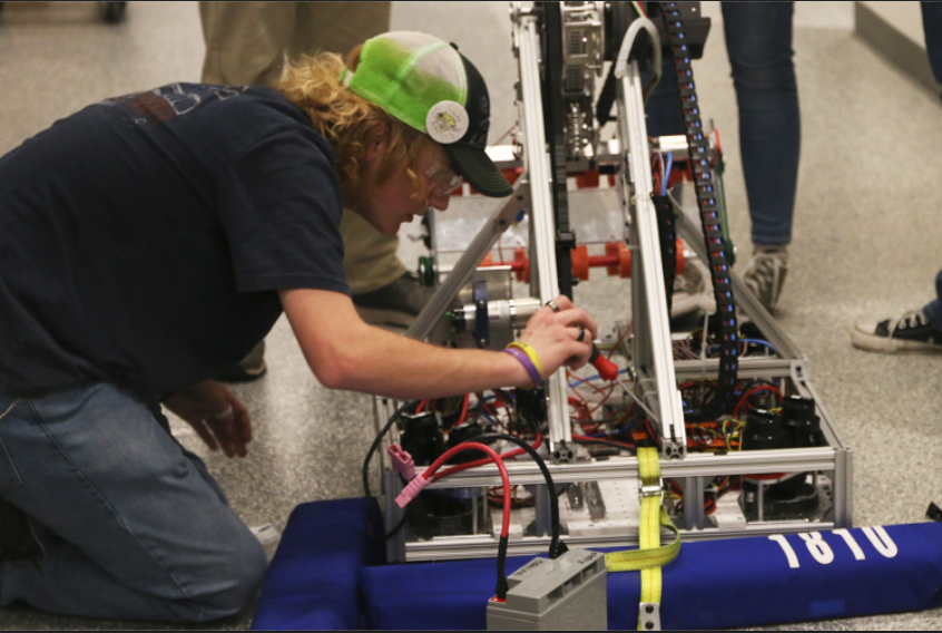 At a team practice, junior mechanical sub-team captain Evan Mack leans over the varsity teams robot, using a screwdriver to carefully secure a part. Thursday, Feb. 23