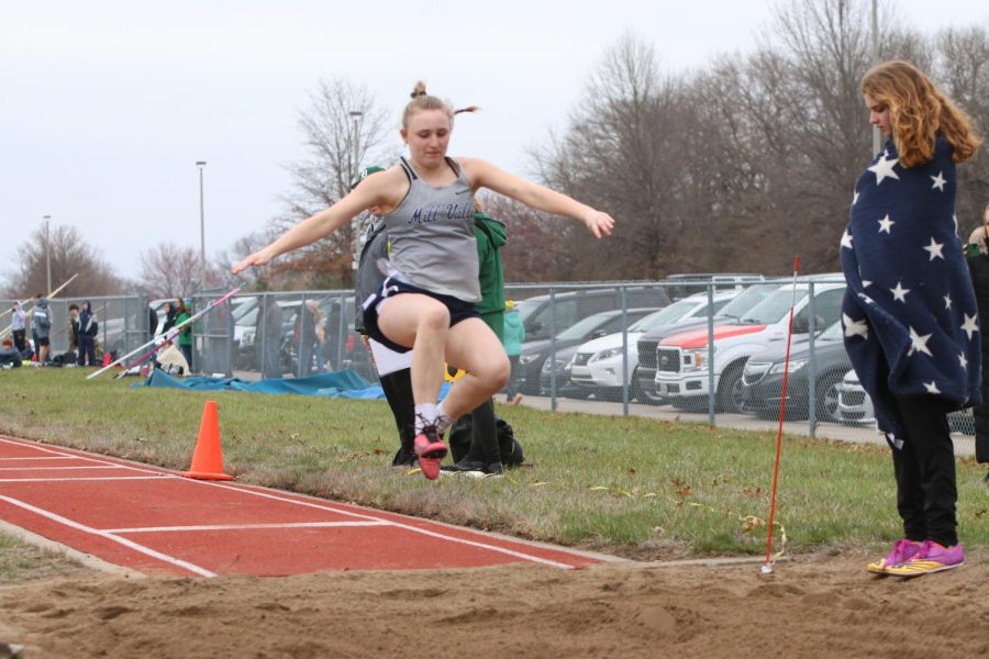 In the air, senior Jayda DeWitte looks down at the sandpit to see where she will land.