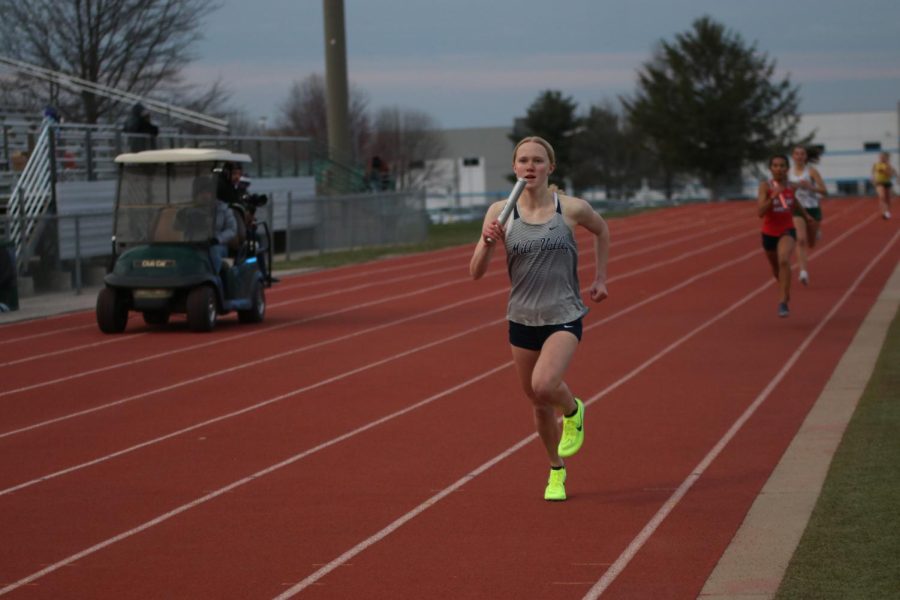 Sophomore Charlotte Caldwell grips the baton as she runs the second leg of the 4x400 meter relay.
